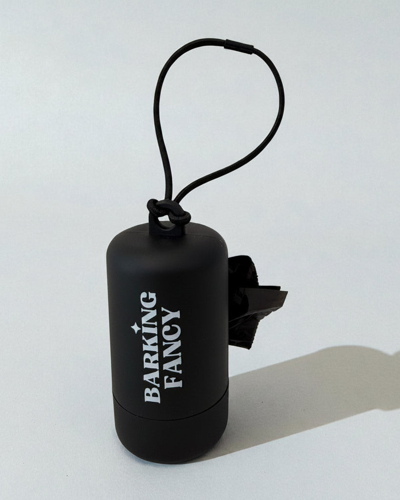 Black pet waste bag dispenser with 'Barking Fancy' branding on a white background